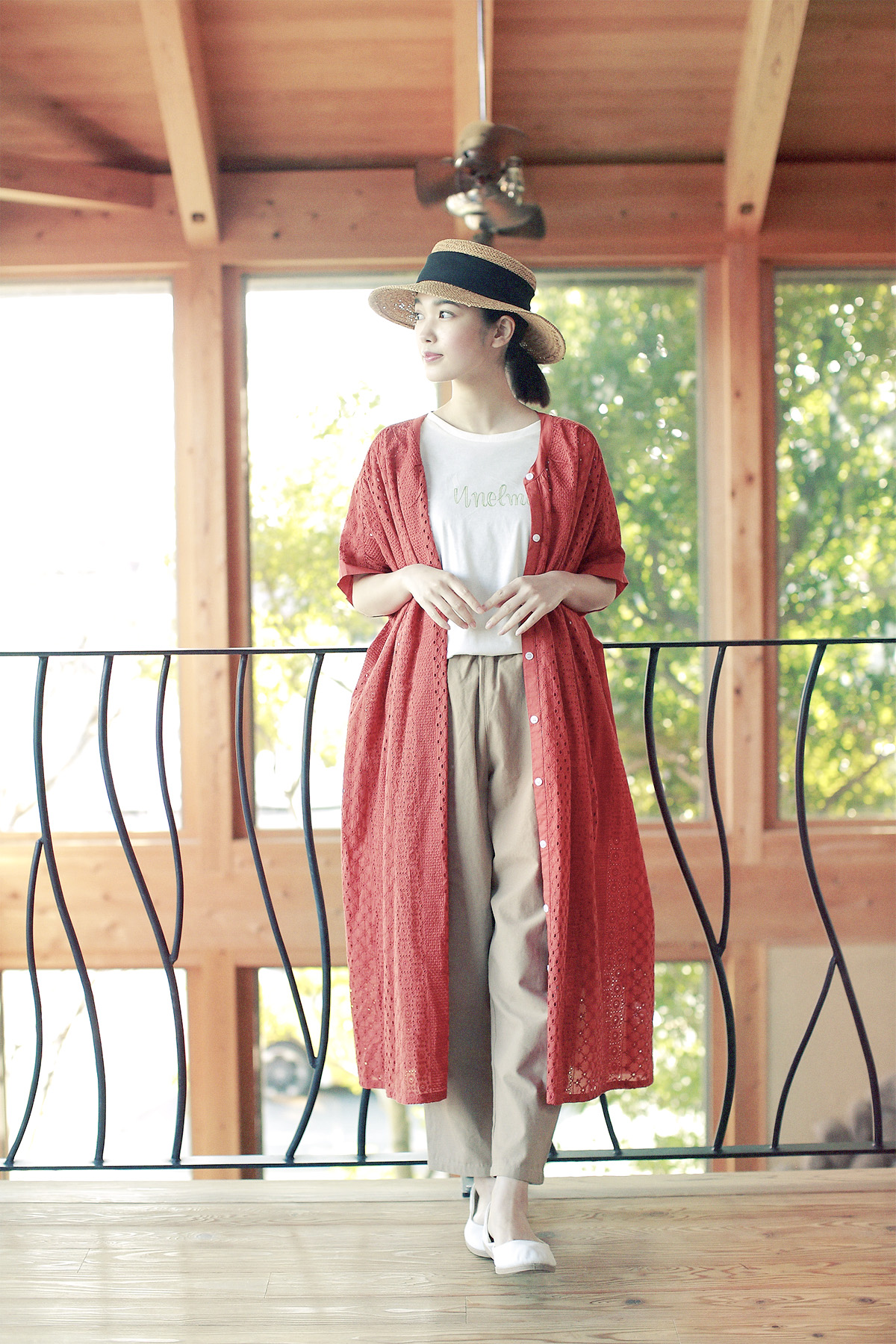 赤いロングカーディガンと麦わら帽子の女性モデルの写真