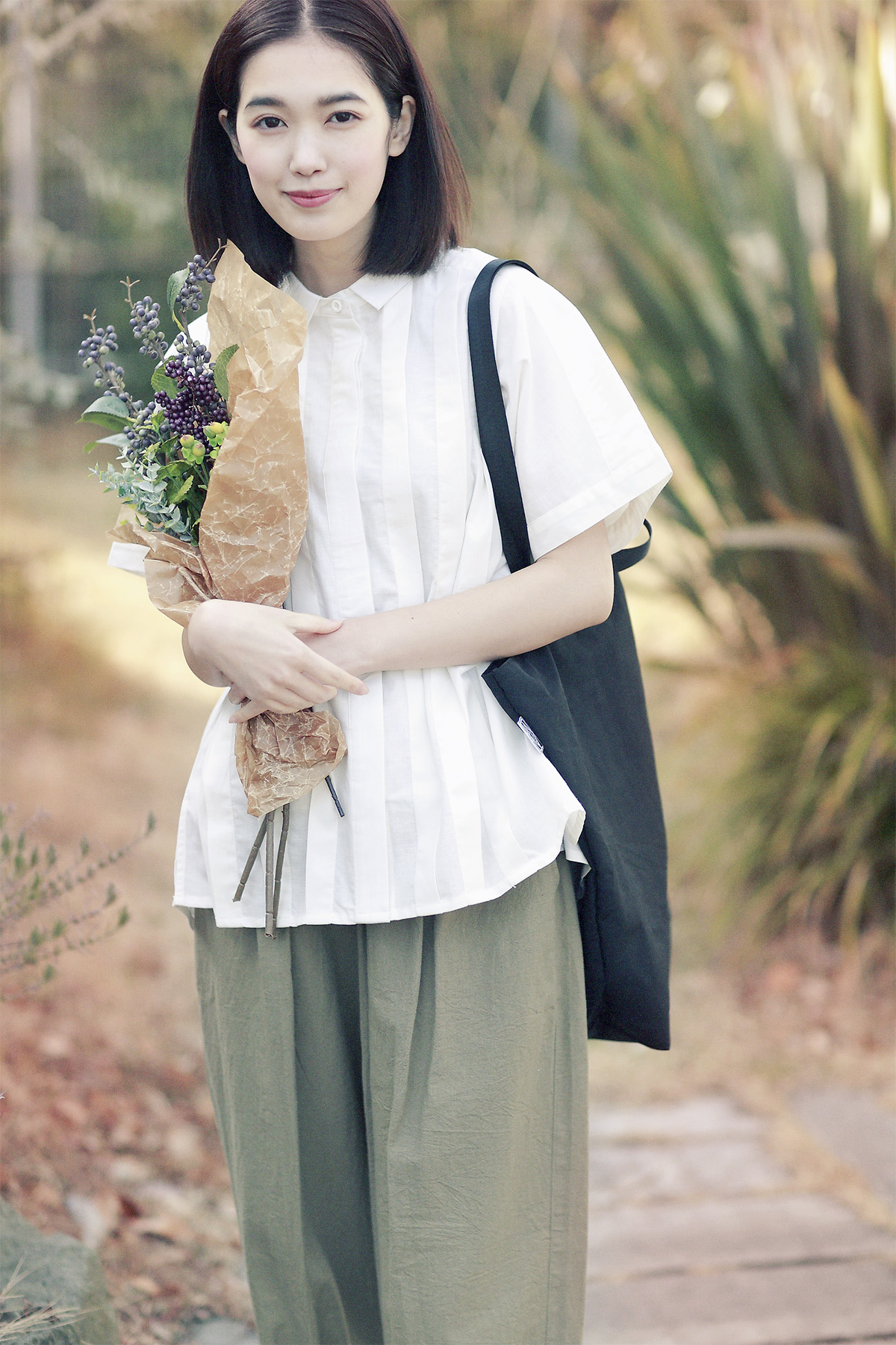 花束を持ったブラウス姿の女性モデル写真