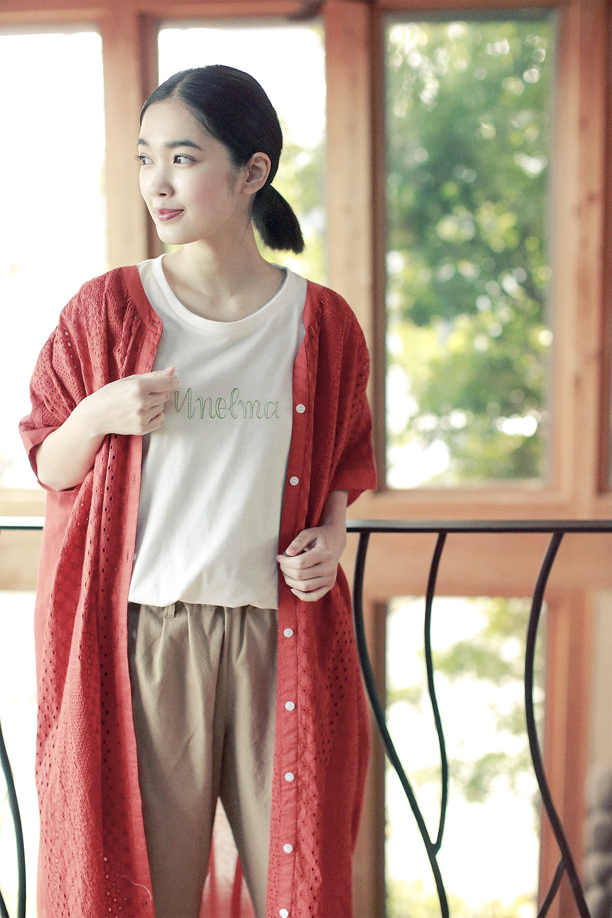 赤いロングカーディガンと麦わら帽子の女性モデルの写真