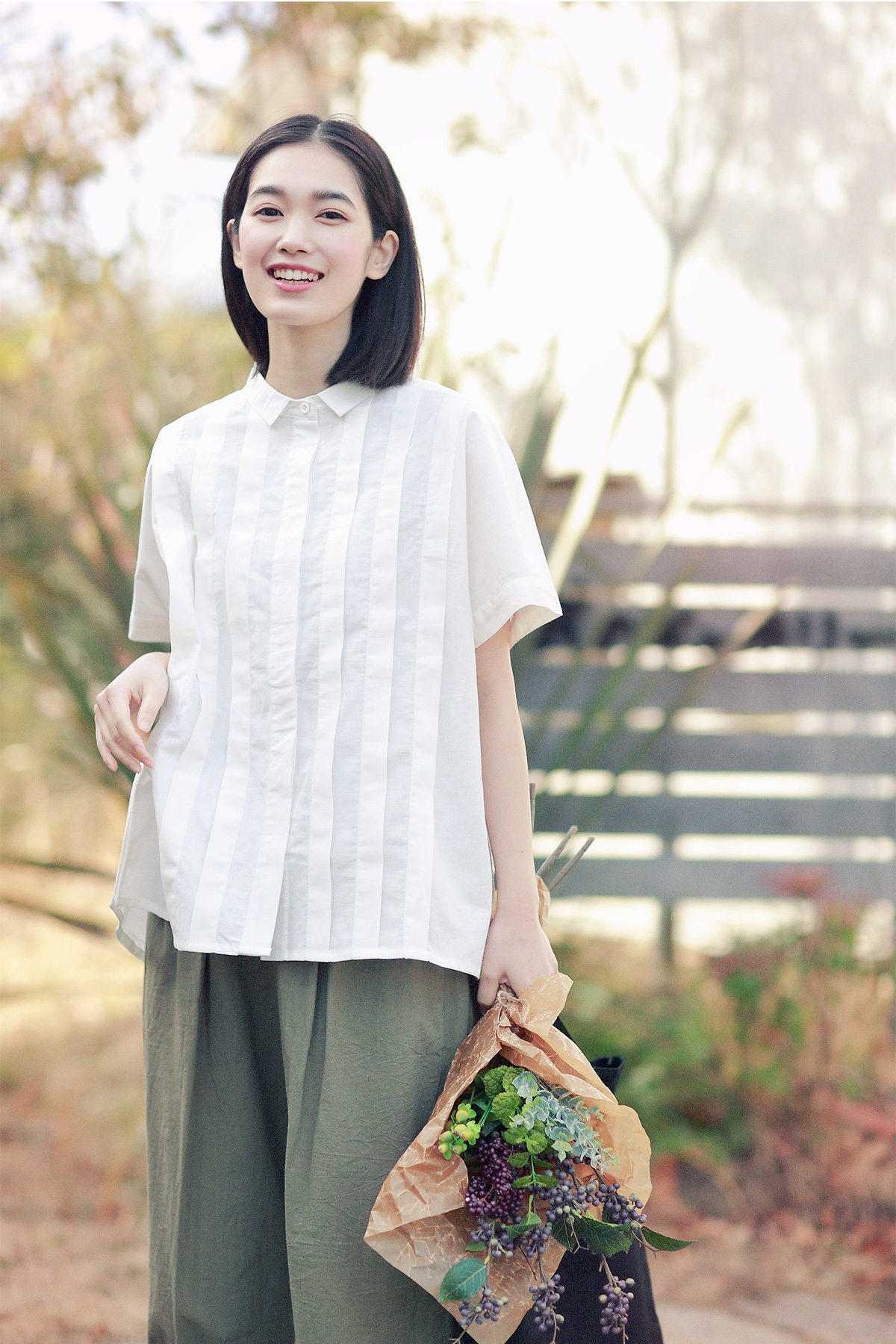 花束を持ったブラウス姿の女性モデル写真