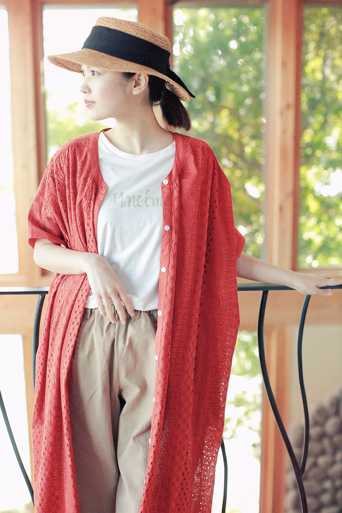 赤いロングカーディガンと麦わら帽子の女性モデルの写真