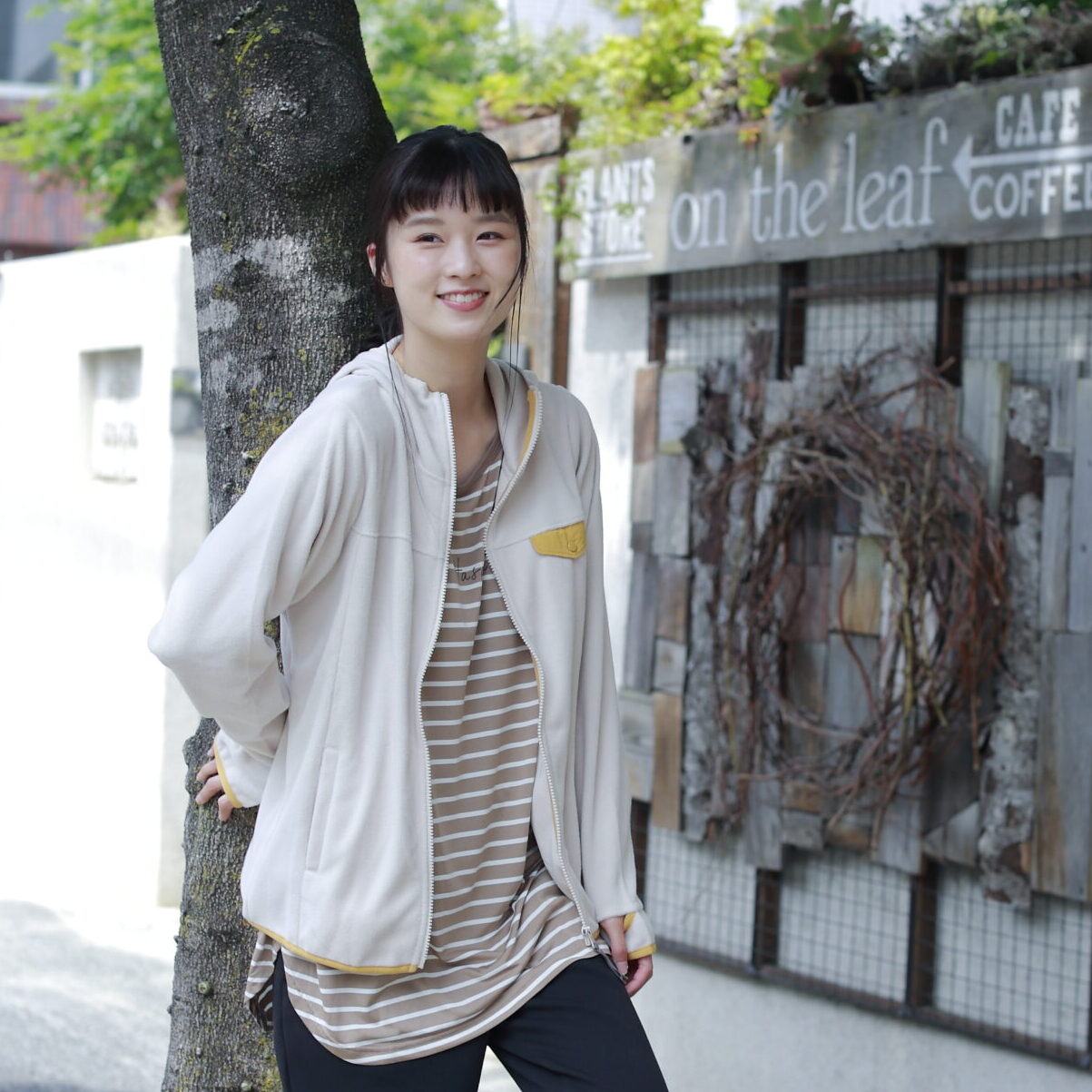 気に寄り掛かる女性モデルの写真