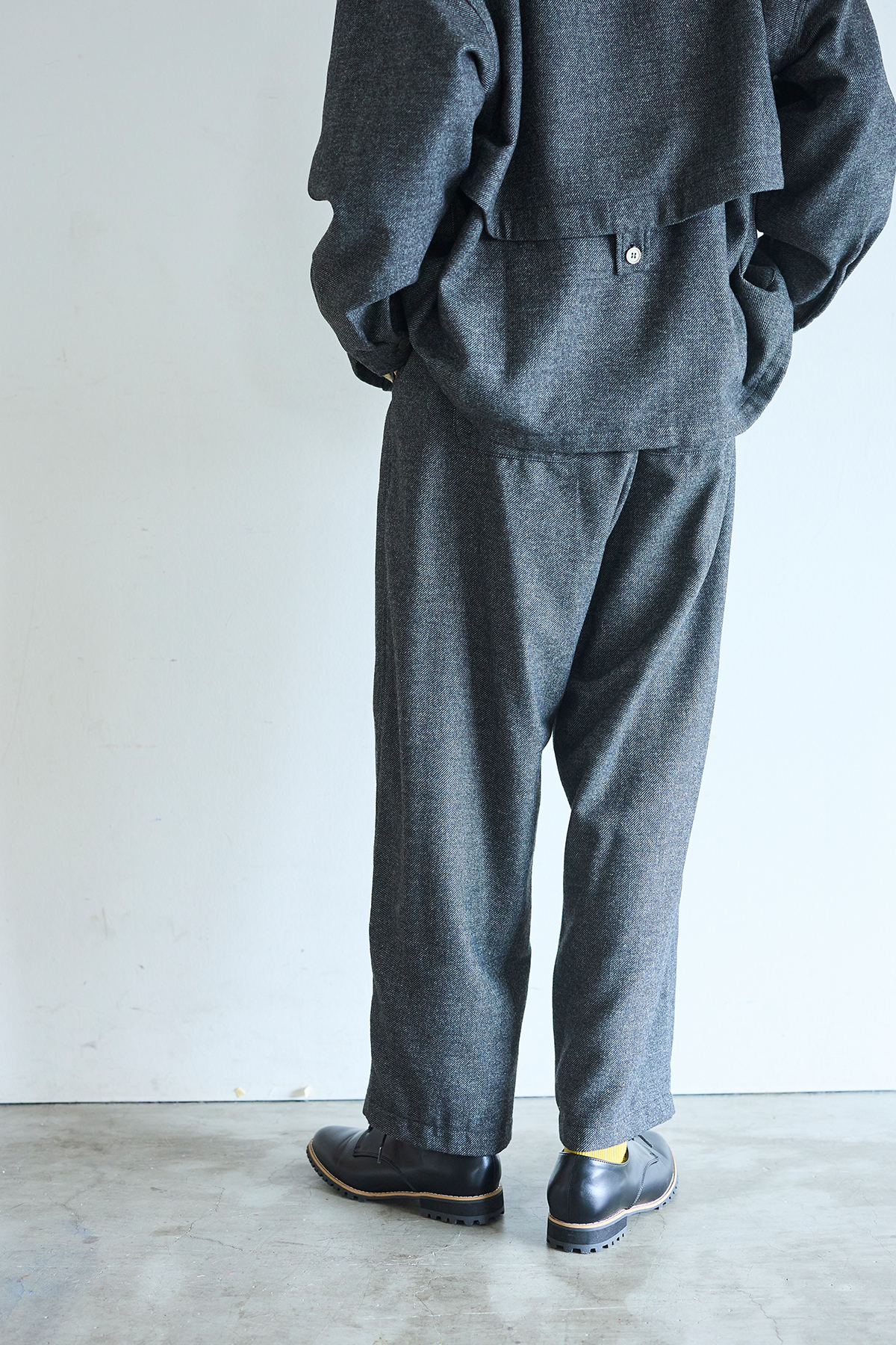 グレーのコートとパンツのセットアップを着た女性モデルの写真